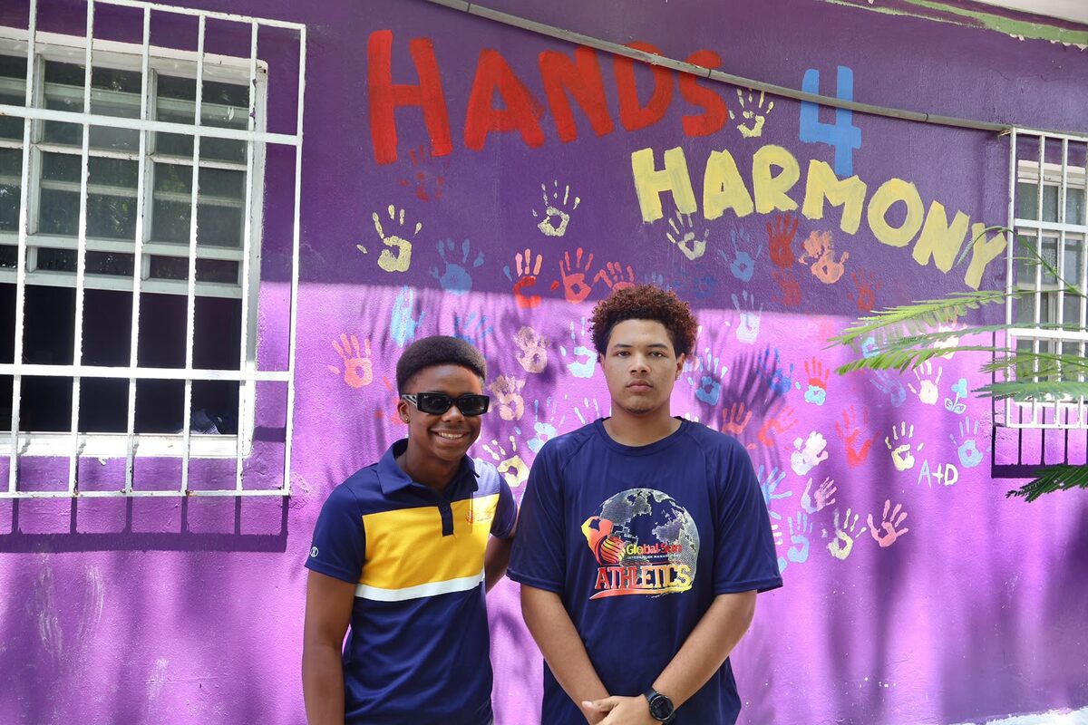 Two Boost Academy students in front of the Hands 4 Harmony mural